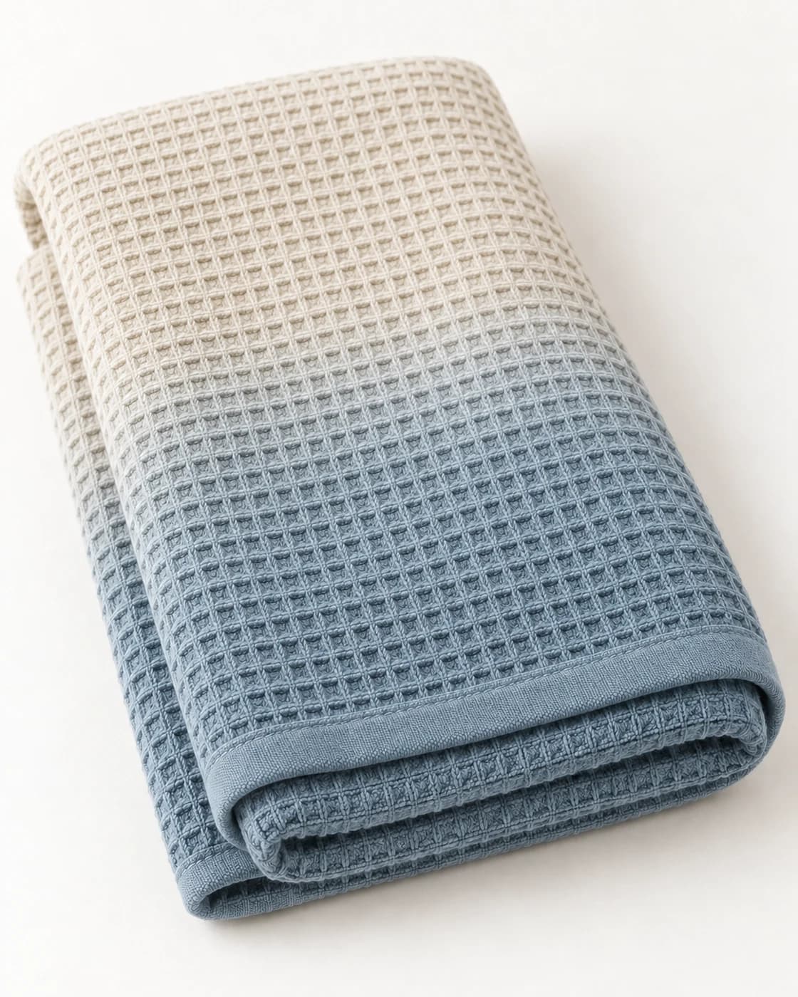 The ombré waffle bath towel in dusty blue, folded to show its ivory-to-colour gradient