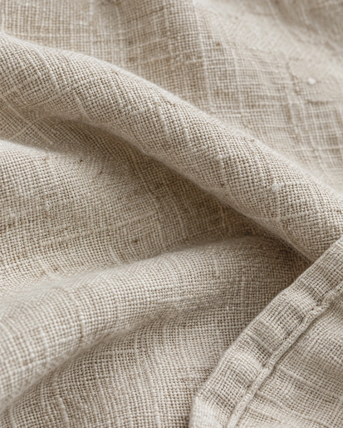 Natural oatmeal linen with fine flax slubs, interlaced threads and a neatly stitched hem
